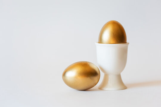 Easter gold eggs on stand on white minimalist background with copy space. premium luxury greeting card with concept of success, wealth and profit