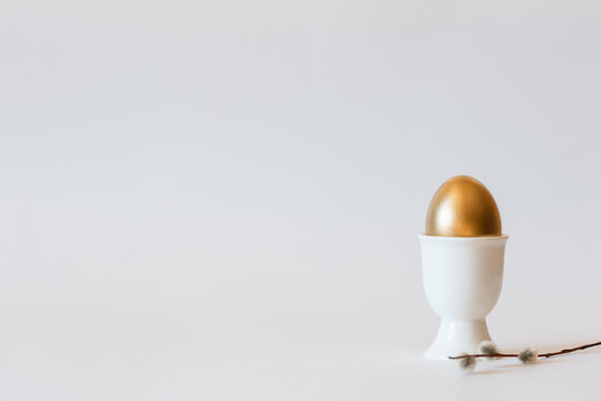 Easter gold egg on standand willow on white minimalist background with copy space. premium luxury greeting card with concept of success, wealth and profit