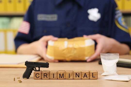 A law enforcement officer focuses on a package wrapped in tape, revealing connections to criminal activity. Nearby, a handgun and white powder hint at a serious investigation in progress.