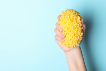 Woman with bath sponge on light blue background, closeup. Space for text © New Africa