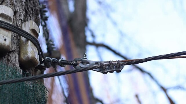 Steel cable fastening system. Steel cable clamps are known as rope clamps or U-shaped clamps. Clamps are used to form loops or connect the ends of cables. Fragment of a rope park fastening