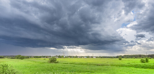 Obraz premium Dark clouds loom over vast green fields
