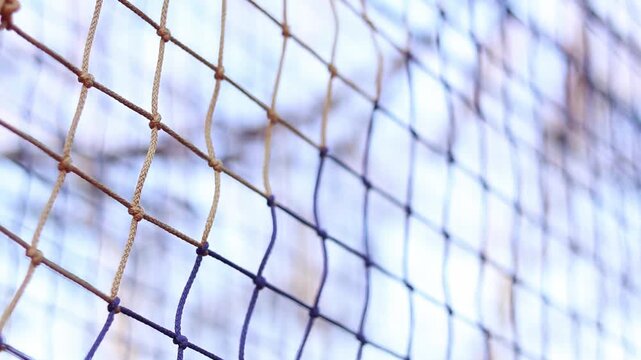 A fragment of a rope tunnel, which is a popular element of rope parks and playgrounds. Weaving a mesh with selective focus. Strong ropes are connected by reliable knots, forming a uniform mesh
