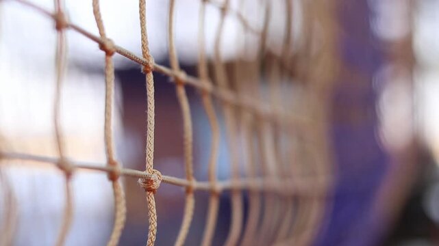A fragment of a rope tunnel, which is a popular element of rope parks and playgrounds. Weaving a mesh with selective focus. Strong ropes are connected by reliable knots, forming a uniform mesh