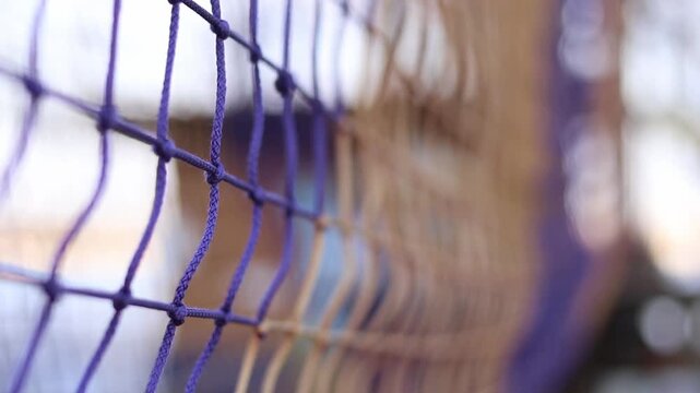 A fragment of a rope tunnel, which is a popular element of rope parks and playgrounds. Weaving a mesh with selective focus. Strong ropes are connected by reliable knots, forming a uniform mesh