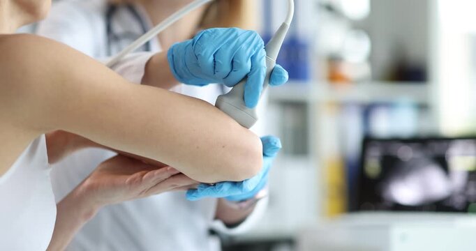 Doctor performs ultrasound scan on woman arm and elbow for medical check. Medical specialist presses probe studying image on monitor for diagnosis