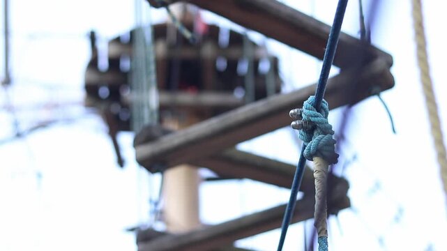 A row of vertically hanging strong ropes with securely tied knots. Fragment of a rope park. Part of the rope is wrapped with a light protective tape. Selective focus