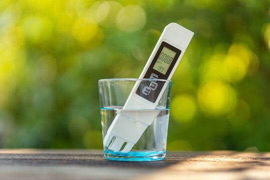 TDS measurement of water. Electronic pH meter in a glass of water. poor water quality, high values of salt impurities, blurred background of nature