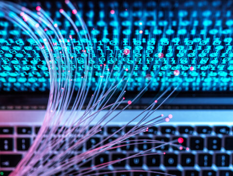 Fiber optic network and binary code on laptop symbolizing data transfer