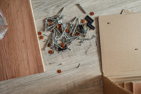 Furniture assembly hardware scattered on wooden floor at home