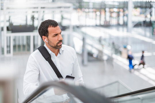Businessman making a phone call on escalator in modern building