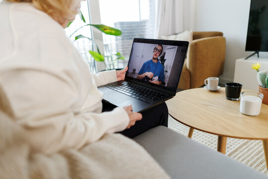 Senior using laptop for virtual medical telehealth consultation at home