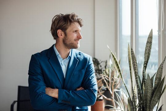 Confident business executive in blue suit looking out office window