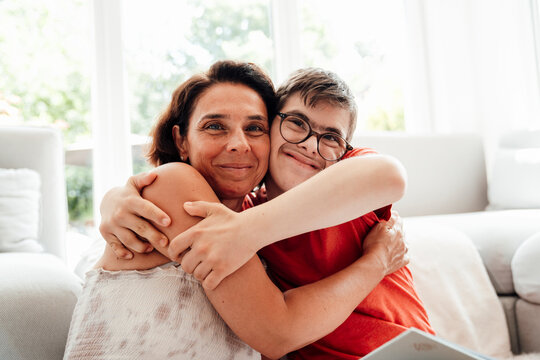 Mother and son with trisomy 21 hugging and smiling at home