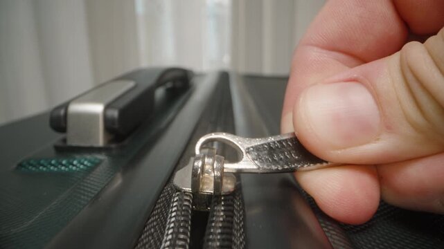 Dolly slider, close up. Fingers pull the zipper shut, securing luggage in anticipation of a journey that promises fascinating exploration and adventure.