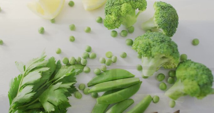 Vertical video: Panning overhead camera showing snap peas and asparagus on white counter for recipe