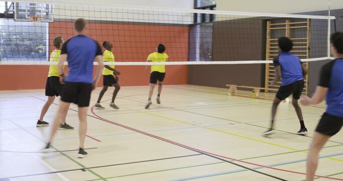 African American man bib tracking, blocking volleyball at net after yellow set at gym, copy space