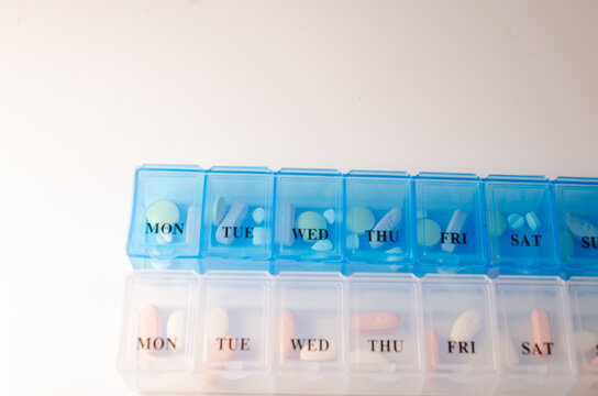Blue pill dispenser containing pills used for helping with daily dose of medicine