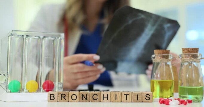Row of wooden blocks spells word Bronchitis near x-ray film and color vials. Doctor woman studies lungs image writing clinical note carefully