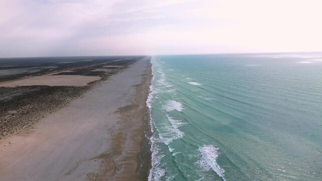 Drone shot of the Caspian Sea coastline in Mangystau Kazakhstan on a misty sunny day empty sandy beach with no people or vehicles turquoise waves and gentle wind natural clean coastal scenery