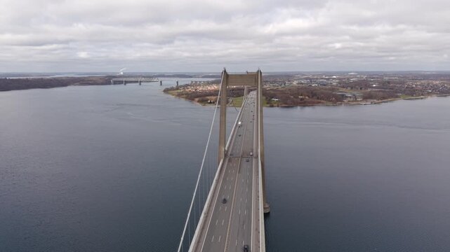 A cinematic drone flight directly over the bridge roadway, emphasizing the symmetry of the suspension cables and the height of the concrete towers as cars pass underneath.