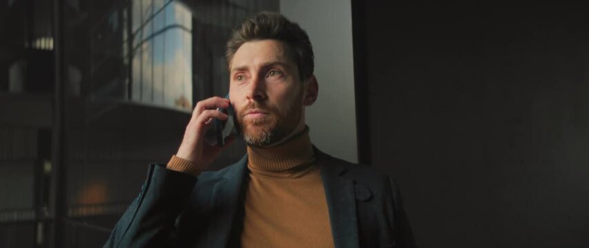 Welldressed Caucasian man uses expressive gestures during important business conversation in bright modern space