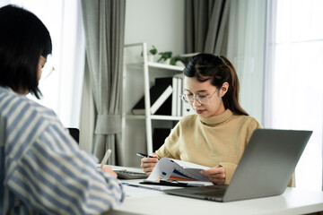 Fototapeta premium Young woman with glasses reviews documents at a desk