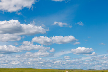 Fototapeta premium Blue sky filled with scattered clouds over open prairie