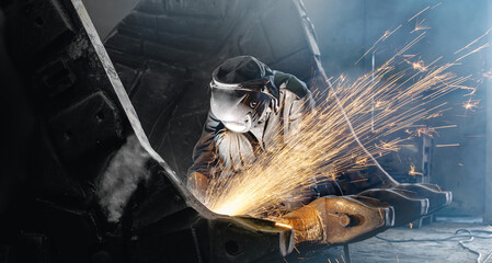 Welder producing shower of sparks while grinding excavator bucket © Parilov