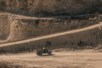 Construction site with old dump truck traveling across a rugged rocky landscape during daytime © Олег Сухенко