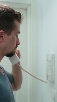 Man answer the intercom and push the button