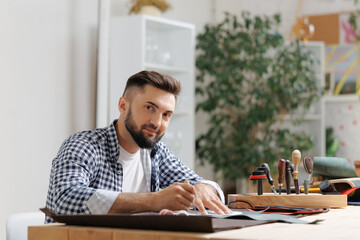Obraz premium Portrait Young caucasian male tailor working with leather in craft workshop, small business
