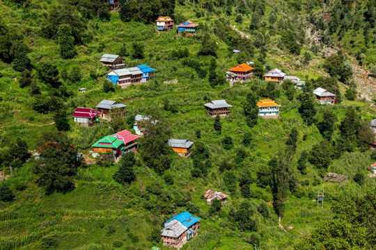View of colourful houses clinging to the verdant hillside, a vibrant tapestry against the lush landscape, a serene escape in Reshian, Azad Kashmir, Pakistan.