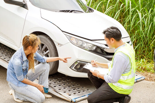 Closeup cars insurance company officers post a list of repairs on work list clipboard according sufferer woman point out the damage on her car