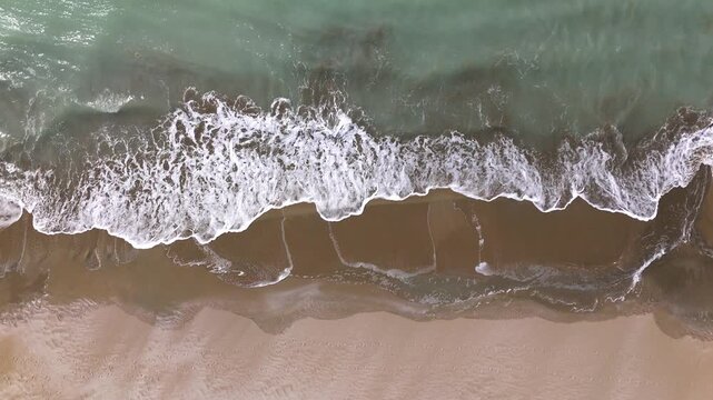 Static drone footage of a horizontal view of the Caspian Sea sandy beach in Mangystau Kazakhstan turquoise waves gently rolling onto the empty shore bright summer scene natural coastal landscape with 