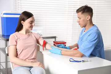 Obraz premium Nurse drawing woman's blood sample in clinic