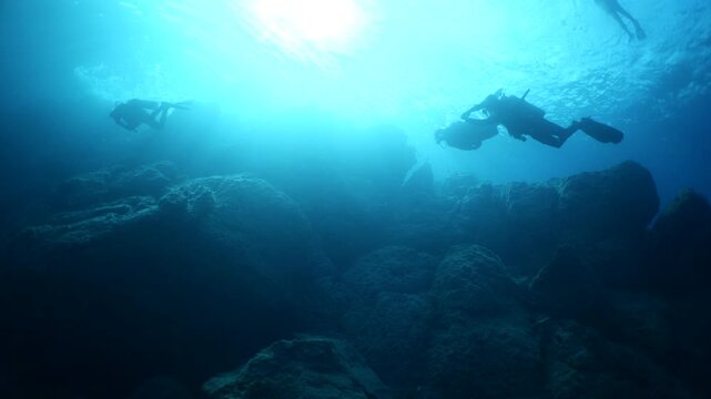 scuba divers exploring underwater with sun beams and rays