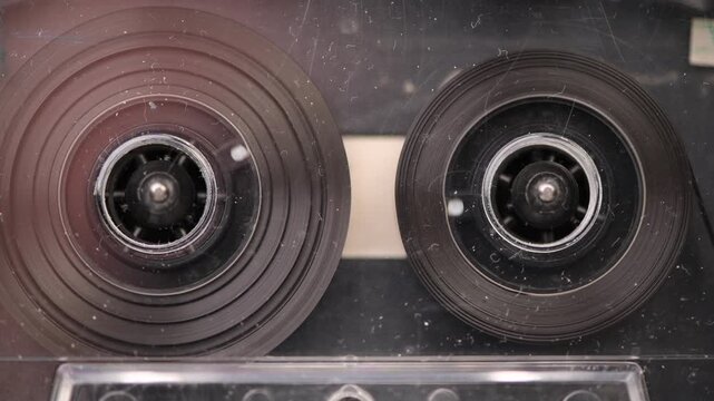 A tape recorder is playing an audio cassette. Close-up. A vintage audio cassette spins on a incoming message label tape used to record sound in a retro cassette player. Recording incoming calls.