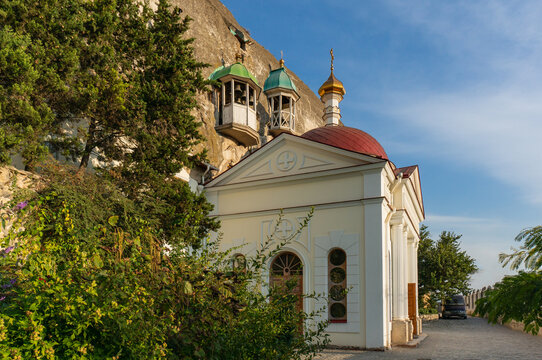 Orthodox Church of Panteleimon Healer of Inkerman Monastery, with its red roof and golden dome is on rocky. Above it, two bell towers with green roofs can be seen. Sevastopol, Crimea - October 9, 2014
