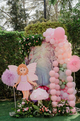 Obraz premium Enchanting outdoor birthday party decor with a fairy cutout, balloons, and floral arrangement in a lush garden setting