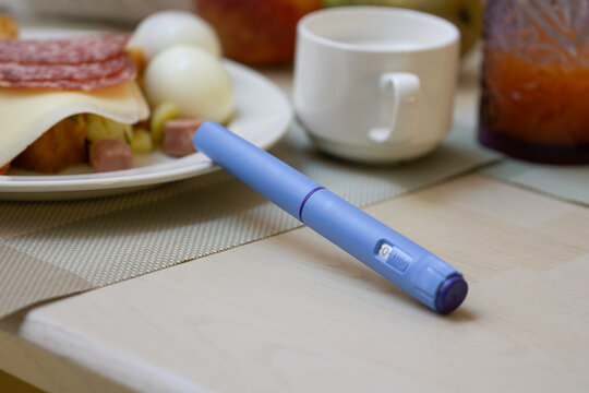 ozempic pen semaglutide injection blue medical device on wooden table with healthy food blurred in background for diabetes management and weight loss concept of healthcare, medicine, pharmacy