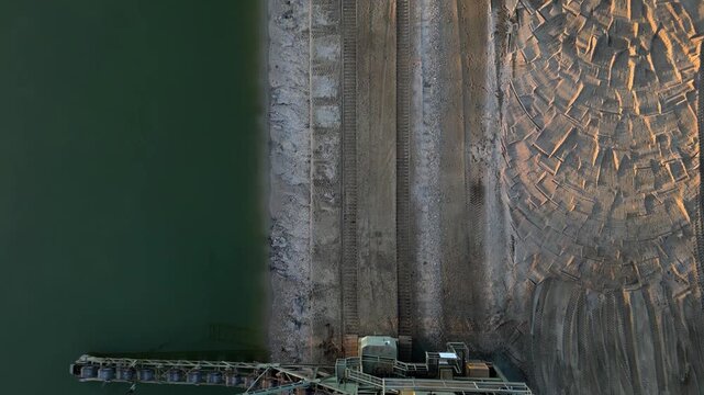 bucket chain excavator massive piece of industrial equipment typically used in open-pit mining or large-scale dredging. operating at edge of water body, likely excavating material from shoreline or fl