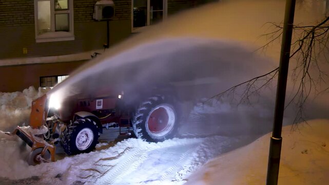 Nighttime snow removal operation with compact loader and street lighting, winter maintenance of urban roads, heavy equipment working in dark conditions