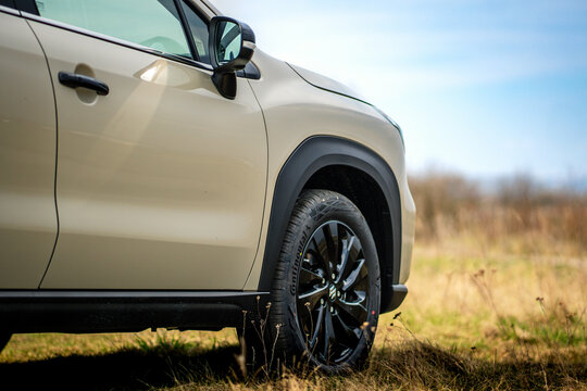 Brno, Czech Republic - March 22, 2026: Detail of the front wheel of a beige Suzuki S-Cross SUV standing outside on a meadow in nature.
