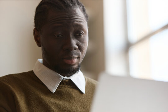 Black young adult man reviewing document, focusing on paperwork. Suitable for corporate training, productivity, finance, or HR content