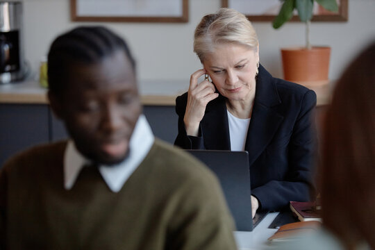 Senior businesswoman reviewing data on laptop, focusing on strategy and decision making. Ideal for corporate leadership, management training, workplace communication