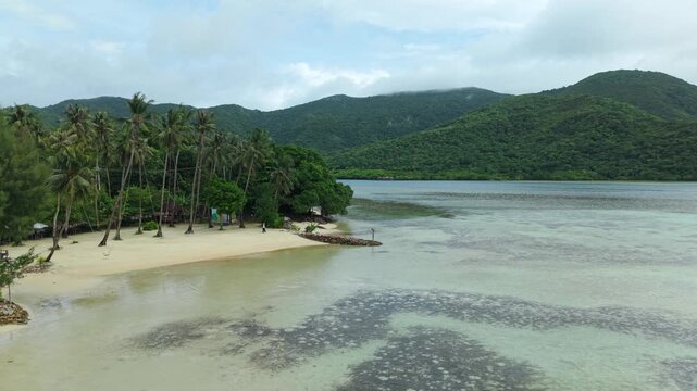 Aerial view of Bobby Beach with crystal clear water, sandy shores and lush green mountains creating a tranquil tropical paradise, Karimunjawa, Central Java, Indonesia.