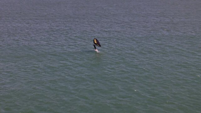 Aerial view of a windsurfer glides across the vast expanse of the water, creating a mesmerizing contrast against the blue sea, Cascais, Lisbon, Portugal.