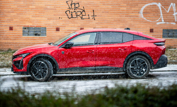 Brno, Czech Republic - December 12, 2025: Red modern SUV Peugeot 408 stands on the street in winter during snowfall. French stylish car.