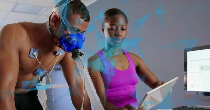 Man leaning on bike breathing into mask, tech tapping tablet showing ECG chart for fitness